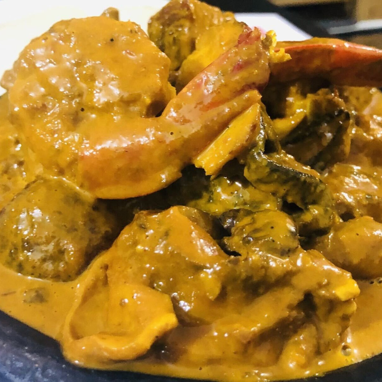A bowl of Urhobo Owho Soup, featuring a thick, savory red broth with pieces of meat and crayfish, traditionally prepared and served with Eba starch.